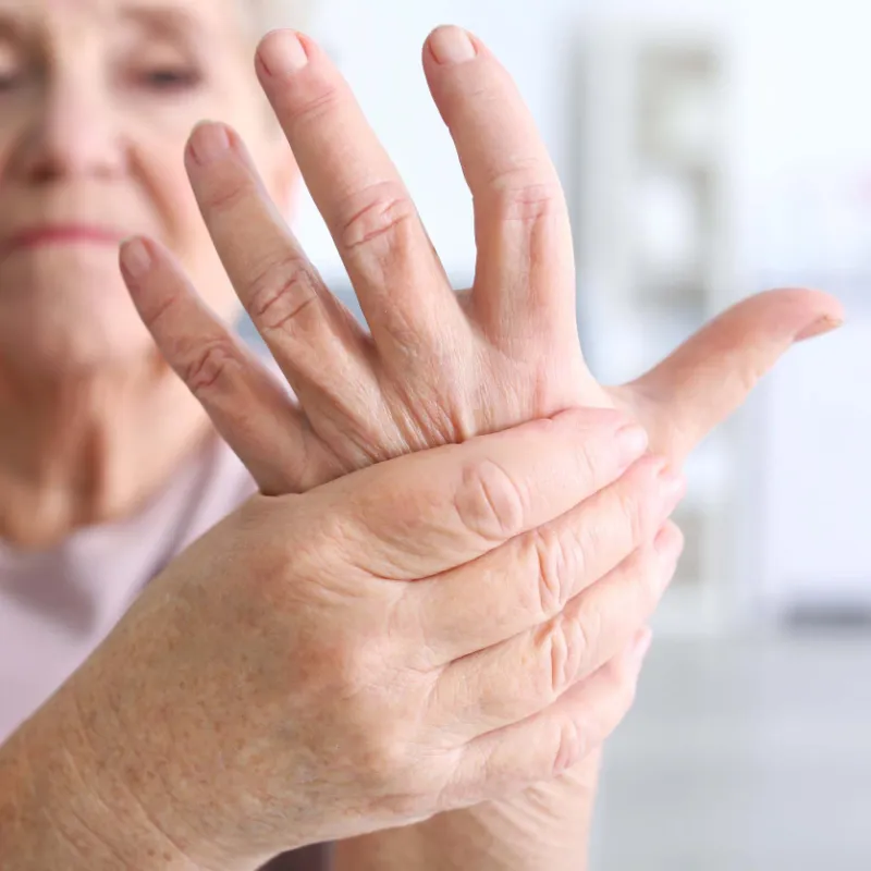 Senior woman rubbing her hand in discomfort.