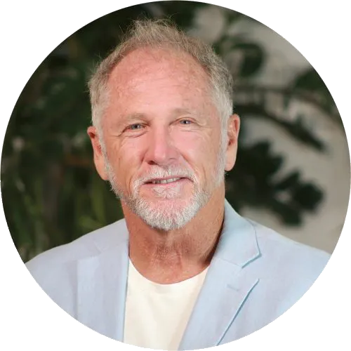 Portrait of older man with white hair and wearing a light blue blazer and white t'shirt