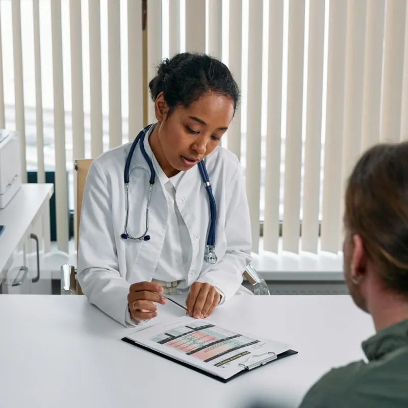 Female physician with white coat going over patient chart with patient