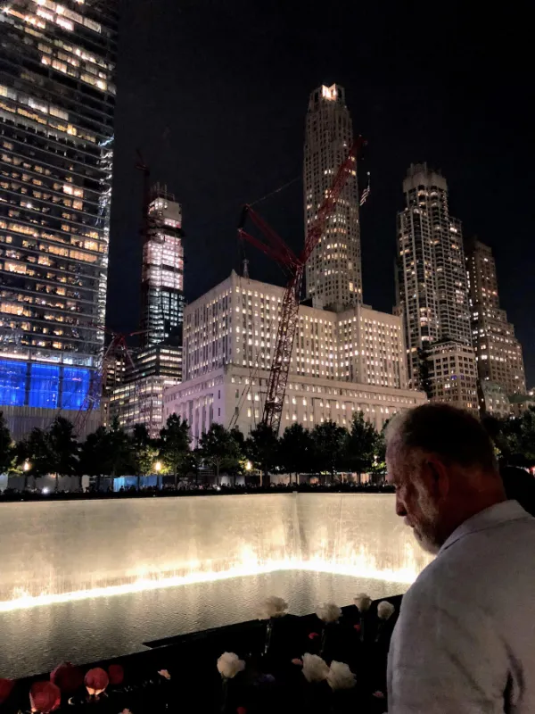 Night time city lights background with man over looking a water feature