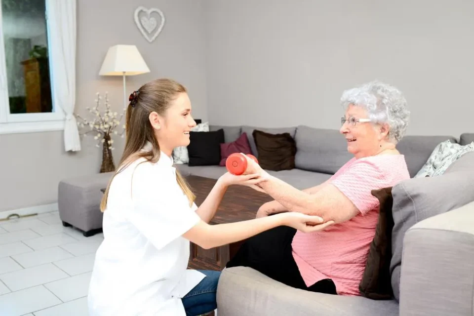 Young therapist woman with long brown hair helping a older senior woman with arm exercises during her Cannabinoid therapy consultation